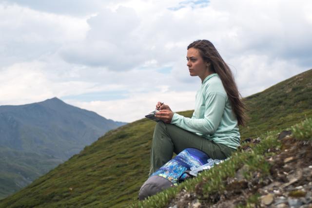 Woman sitting on side of mountain.