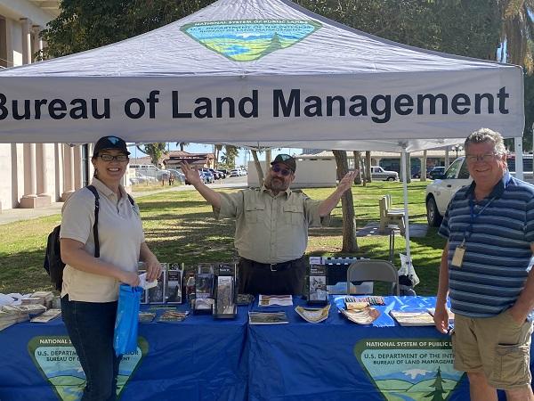 A man gesturing with his hands at the BLM booth with a woman and another man on either side of him. 