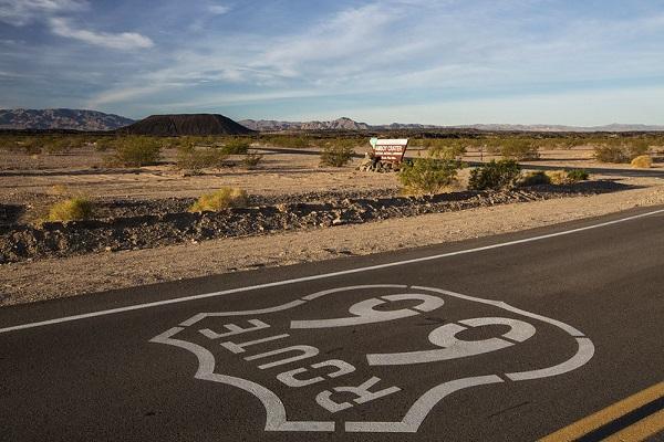 up-close view of Route 66 with brown dirt and hills in the background