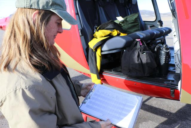 Woman looking at clipboard near a helicopter