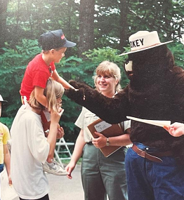 Blonde woman ranger talking with visitors at a park.