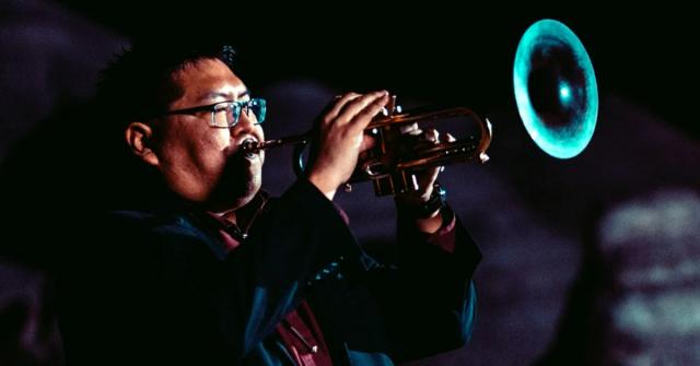 Delbert Anderson standing and playing the trumpet in a concert performance.