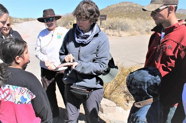 BLM volunteer, Margaret "Marglyph" Berrier, shows participants an arrowhead and piece of broken pottery found along the trail.