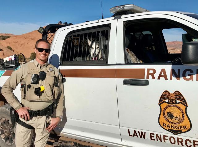 A BLM uniformed ranger standing in front of a truck.