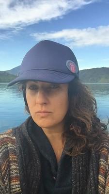 A woman in a blue baseball cap in front of a lake.