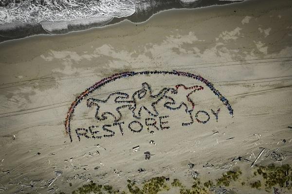 Aerial view of ochre sea stars forming the words "Restore Joy" in the sand. 