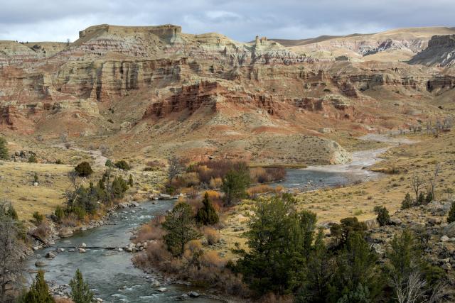 Dubois Badlands Wilderness Study Area: Scenic landscape of red cliffs and a blue stream