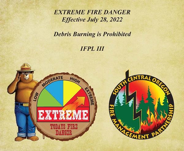 Smokey Bear standing next to chart showing that fire danger level is set to Extreme