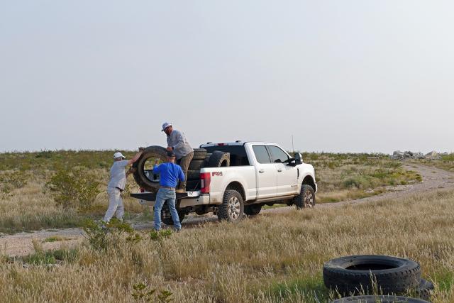 Volunteers from LM Energy load tires into the bed of a pickup truck during 2021 National Public Lands Day.