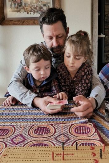 Kevin Donoher sitting down with two children and a deck of cards. 