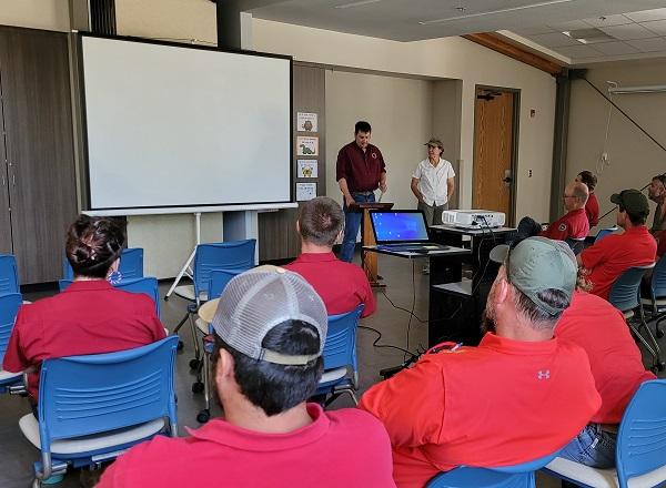 WGFD Terrestrial Habitat Biologist Todd Caltrider presents BLM Fire Ecologist Jennifer Walker with an Appreciation Award at a small ceremony in June 2022 while people look on. 