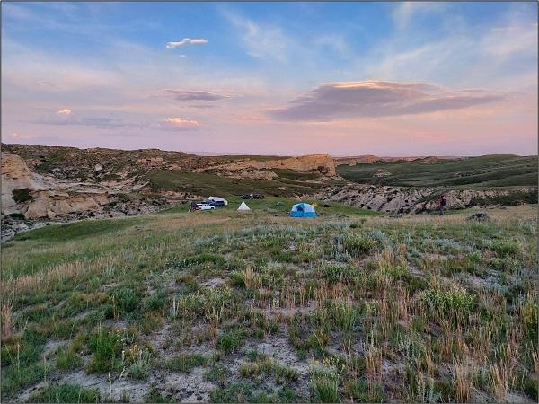 Tents set up with the background of a scenic landscape and the setting sun.