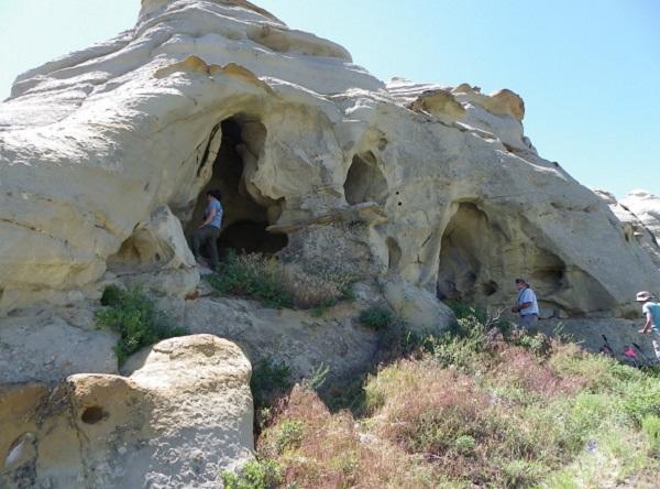 Volunteers in blue shirts entering a sandstone rock outcrop.