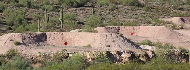 a desert landscape with earthen berms and red circular targets