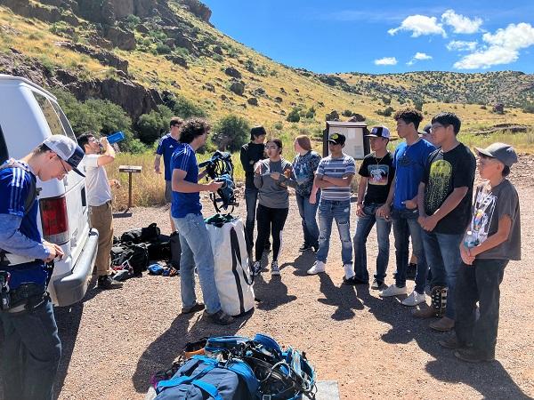 A New Mexico Tech Climbing Club instructor speaks to a group of students gathered in a circle.