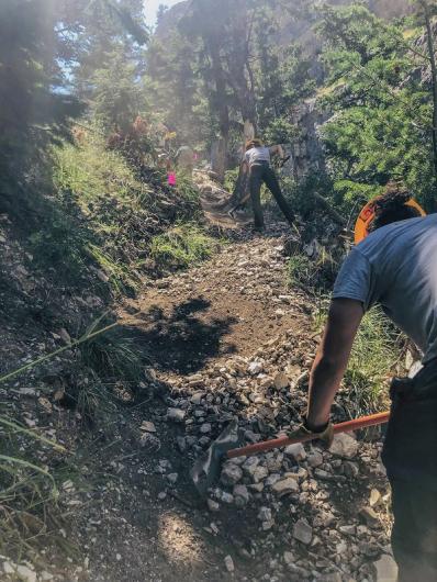 MCC crew members using equipment to clear fallen rock along the trail.