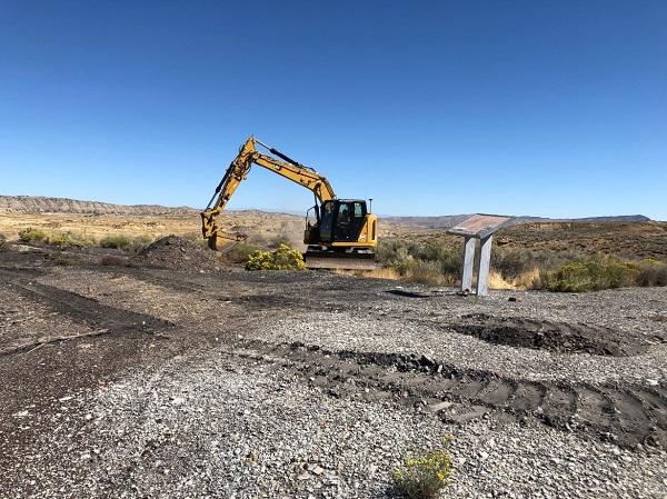 A yellow crane with gravel in front of it. 