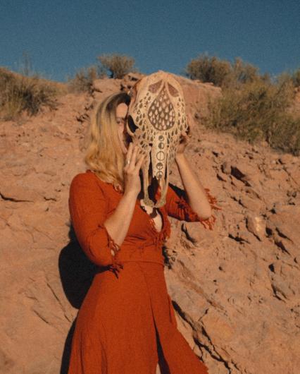 Photo of Walck with a decorated animal skull in a desert landscape.