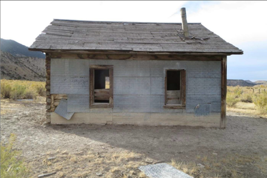 A small one room school building with a stove pipe on the roof.