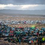 Vehicles take as far as the eye can see with mountains and clouds in the background. 