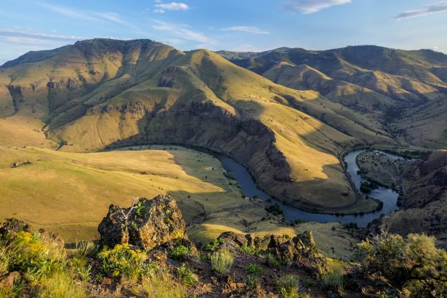 Oblique view of grass covered rolling hills above the winding Deschutes River in central Oregon.