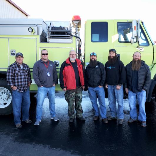 Five individuals smiling standing in front of a fire truck that has just been transferred to the Parowan Fire Department.