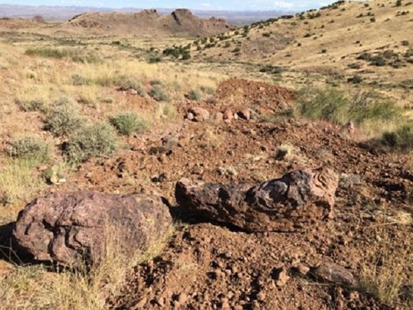 A rocky brown road surrounded by brown grass.