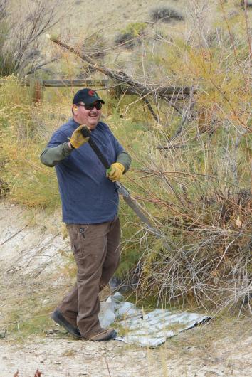 A man cutting saltcedar with a long tool.