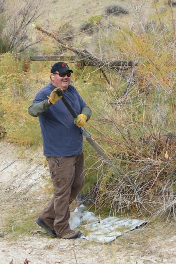 A man cutting saltcedar with a long tool.