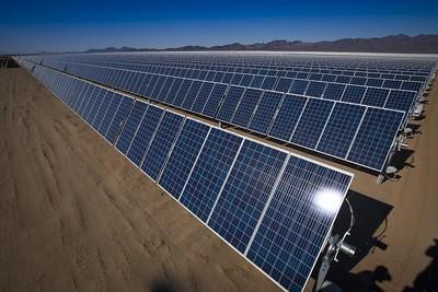 Rows of solar panels with mountains in the background. 