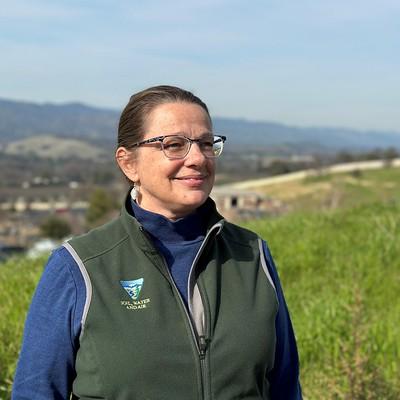 Portrait of a woman in glasses standing on rolling hills.