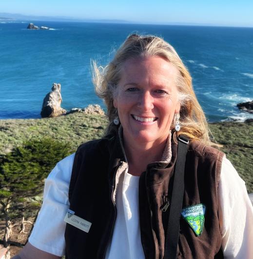 A woman in the foreground with Ocean and rocks in the background.