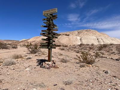 A road sign with many arrow in the middle of the desert.