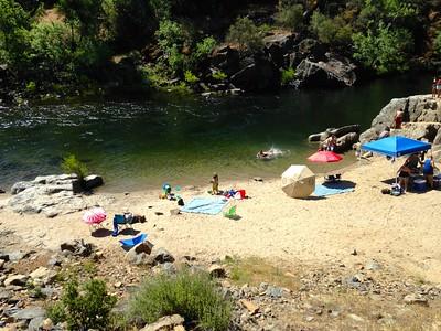 Beach tents line the shores of the forested Merced river.