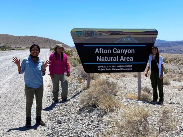 Women standing next to the entrance to a canyon