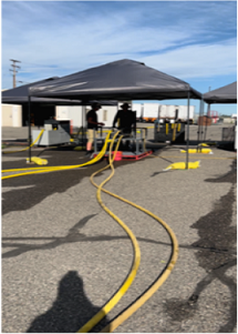 yellow fire hoses running across a paved area, with building in the background