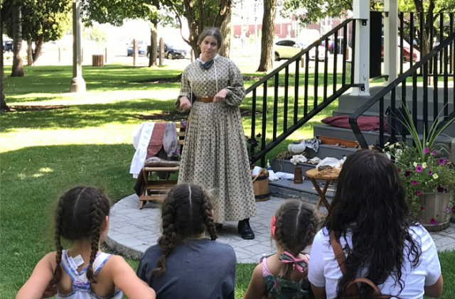 person in old time costume giving a presentation to children