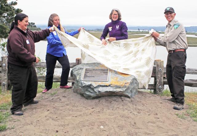 People remove a tarp from a rock.