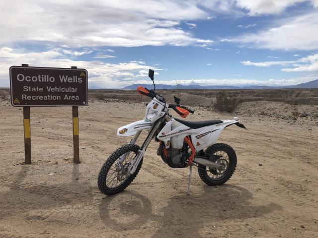 Dirt bike next to a sign in the desert.