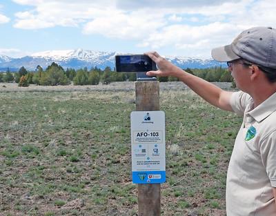 A person scans a qr code and takes a picture of a field