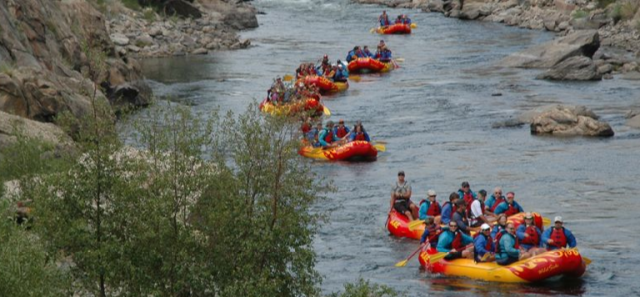 Many rafts full of people floating down a river.