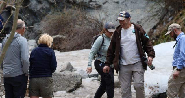 Several people having a discussion on a slightly snowy trail. 