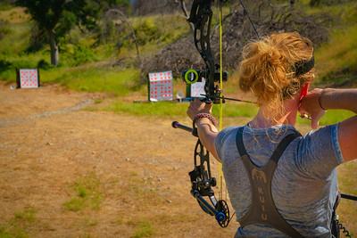 Archer pulls and aims arrow at haystack