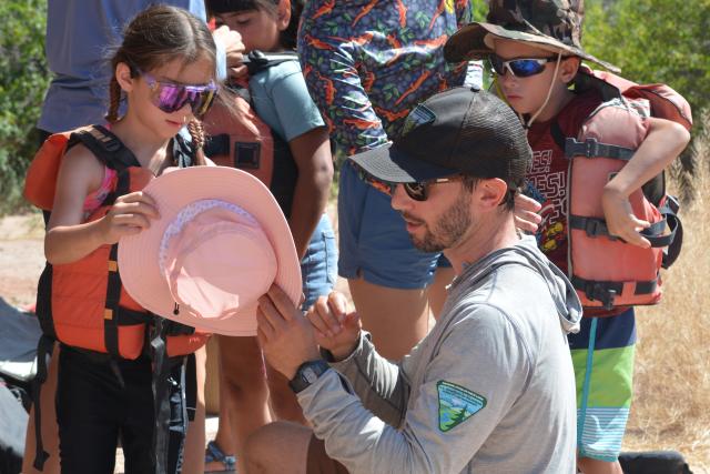 A Park Ranger helping a youth with their personal protective equipment.