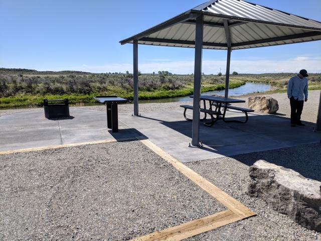 Picture of campsite with shade cover and fire ring at Silver Creek Campground.