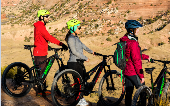 Three women standing with their bikes in a canyon. 