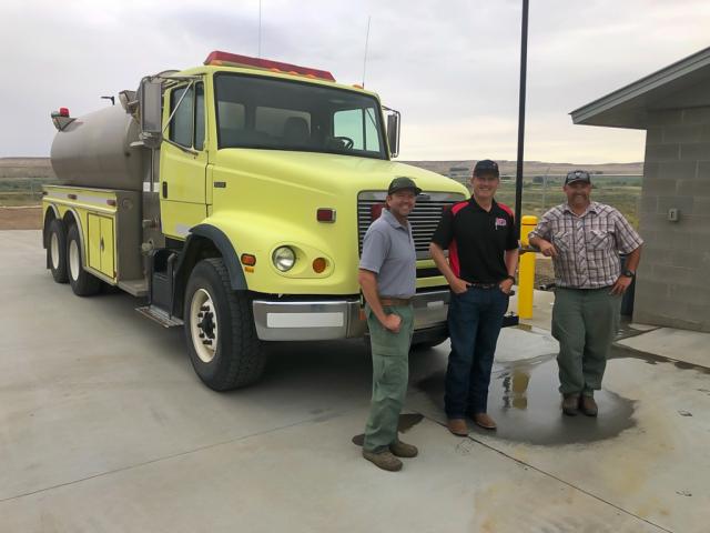 Men standing in front of donated water tender for wildfire suppression. (BLM)