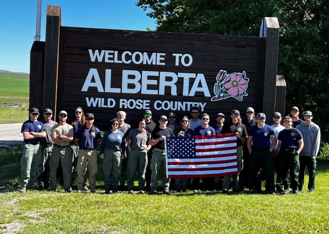 A photo of the Northern Utah Regulars standing in front of the Welcome to Alberta sign in Alberta, Canada.