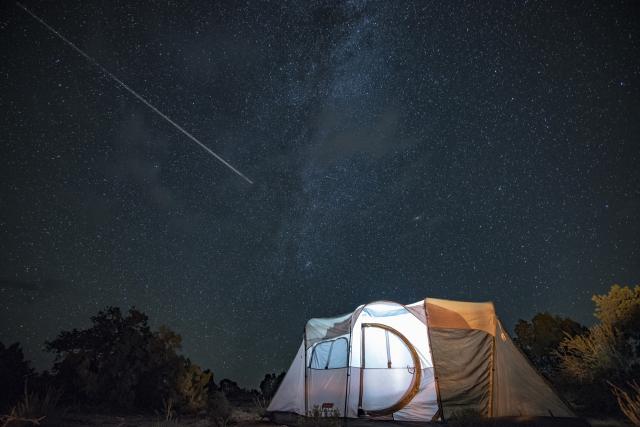 a glowing white tent sits underneath a sparkling night sky of stars.