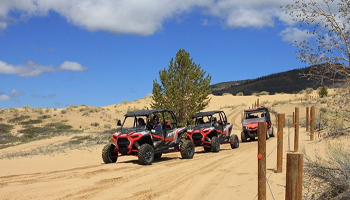 Several off road vehicles lined up on sand. 